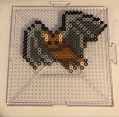 a beaded animal is sitting on top of a piece of clear plastic with black dots