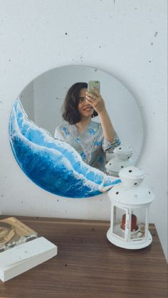 a woman taking a selfie in front of a mirror with a wave painted on it