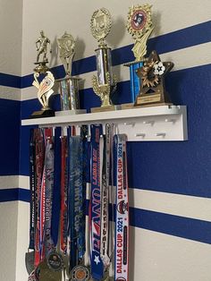 several medals are hanging on a shelf in a room with blue and white striped walls