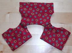 three pieces of red and blue patterned fabric sitting on top of a wooden floor next to each other