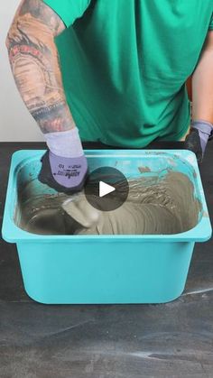 a man in green shirt pouring cement into a blue container