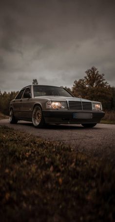 a car parked on the side of a road in front of some grass and trees