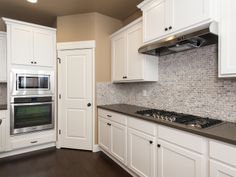 a kitchen with white cabinets and black counter tops