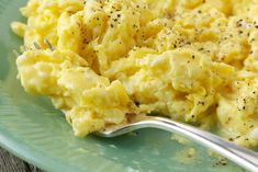 scrambled eggs on a green plate with a fork