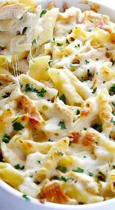 a pasta dish with chicken, cheese and parsley in a white casserole dish