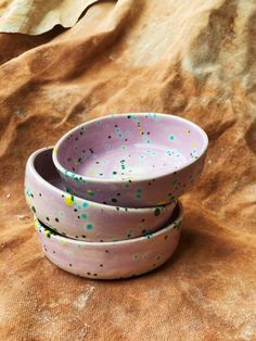 three purple bowls with sprinkles sitting on top of a brown table cloth