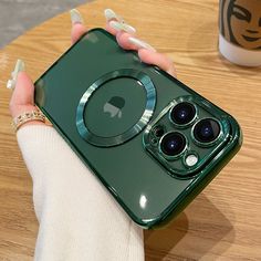 a woman's hand holding an iphone case in front of a coffee cup on a table