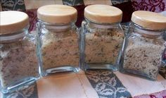 four glass jars filled with different types of spices and seasonings on top of a table