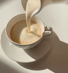 a cup of coffee being poured into it