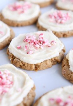 cookies with white frosting and pink sprinkles on top are arranged in rows