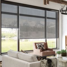 a living room filled with furniture and windows covered in blind shades on the window sill