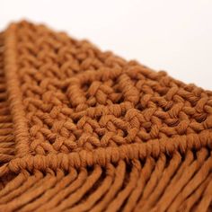 a brown knitted blanket laying on top of a white surface