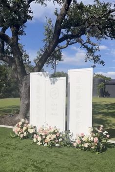 two large white plaques sitting on top of a lush green field next to a tree