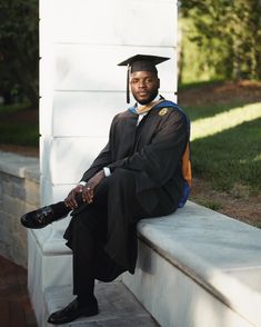 a man in a graduation gown sitting on a bench