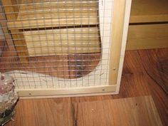 a cat in a cage sitting on the floor next to a wooden door and window