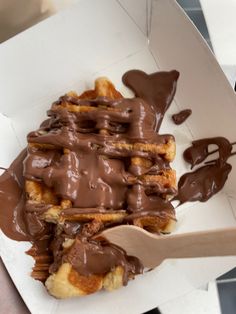 chocolate drizzled on top of bread in a box with a wooden spoon