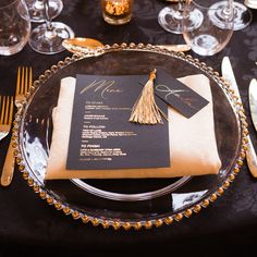 a black and gold wedding table setting with menus, silverware and place settings