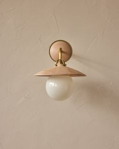 a light fixture on the wall with a white ball hanging from it's side