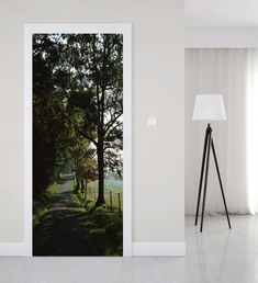 an open door to a white room with trees and grass on the ground in front of it