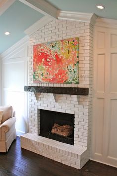 a living room with a white brick fireplace and large painting on the wall above it