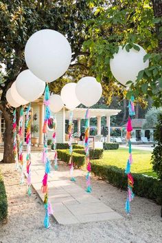 some balloons and streamers are hanging from the trees in front of a white house