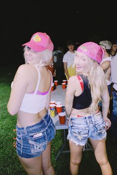 two young women standing next to each other in front of a table with cups on it