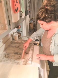 a woman standing in front of a counter cutting something with a pair of scissors on it