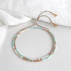 Say hello to the Tarifa bracelet!  This delicate little beauty is inspired by the Spanish coastal town of Tarifa with it's white sandy beach, clear aqua water and terracotta roof tops.  A beautiful dainty double wrap silk bracelet with green aqua, white and copper coloured glass beads with silver accent beads on a beige silk cord. Fits an average wrist size of 6-7 inches and  Extends to maximum of 8.5in to fit over the widest part of the hand. If you have a small wrist and hands and would like a smaller bracelet please contact me. Super easy to put on and tighten, lightweight and comfortable. Displayed in one of our pretty gift boxes, so fantastic as a present for a friend or to yourself! Matching necklace https://www.etsy.com/uk/listing/1067274566/delicate-beaded-necklace-aqua-and-copper Roof Tops, Terracotta Roof, Silk Bracelet, Double Wrap Bracelet, Hippie Bracelets, Small Bracelets, Green Aqua, Coastal Town, Silver Bead Bracelet