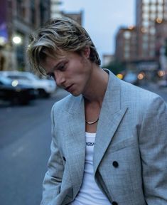 a young man in a suit is standing on the street looking at his cell phone