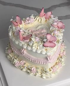 a heart shaped cake with pink butterflies on it's sides and white frosting