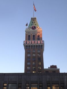 a tall building with a clock on the top and an american flag flying above it