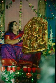 a woman sitting in front of a golden statue