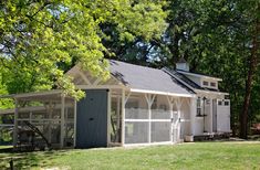 a small white shed sitting in the middle of a lush green field next to trees