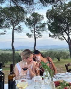 two women sitting at a table with wine glasses