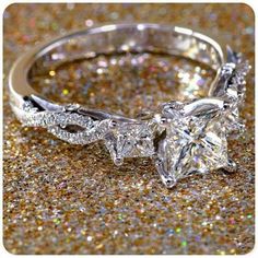 an engagement ring with a princess cut diamond in the center on glittery background,