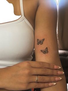 a woman's arm with two small butterflies on the left side of her arm