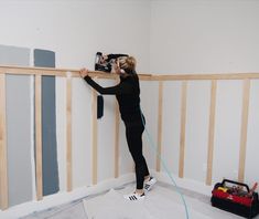 a woman is painting the walls in her house with paint rollers and a power drill