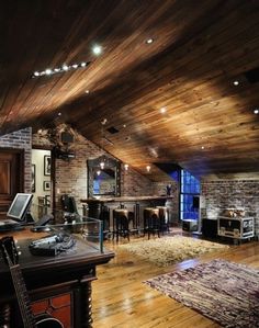 a living room filled with lots of furniture and wooden floors next to a brick wall