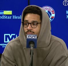 a man in a hoodie sitting at a microphone