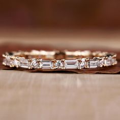 a wedding band with baguettes and diamonds on the side, sitting on a wooden surface