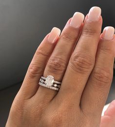 a woman's hand with a wedding ring on it and an engagement band in the middle