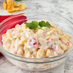 a glass bowl filled with macaroni salad and garnished with cilantro