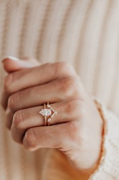 a woman's hand wearing a gold ring with a small white flower on it