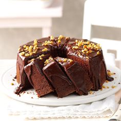 a chocolate cake with nuts on top sitting on a white plate