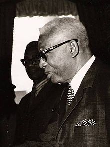 black and white photograph of an older man with glasses looking at something in his hand