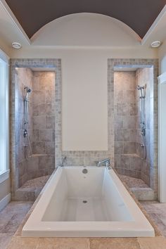 a large white bath tub sitting inside of a bathroom next to two walk in shower stalls