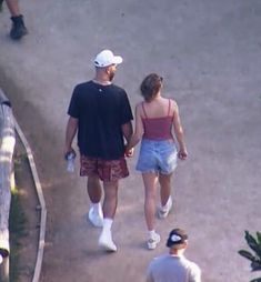 a man and woman walking down the street holding hands while wearing white tennis shoes with their backs to each other