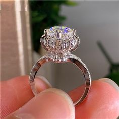 a close up of a person's hand holding a ring with a diamond on it