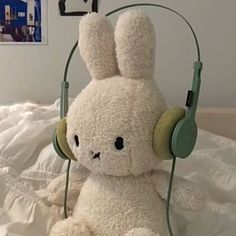 a white stuffed animal with headphones on it's ears sitting on a bed