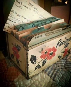 an open file box sitting on top of a bed next to a pile of papers